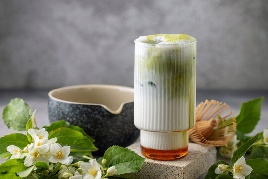 Green jasmine milk with macha tea in glass with jasmine flowers. Trendy drink