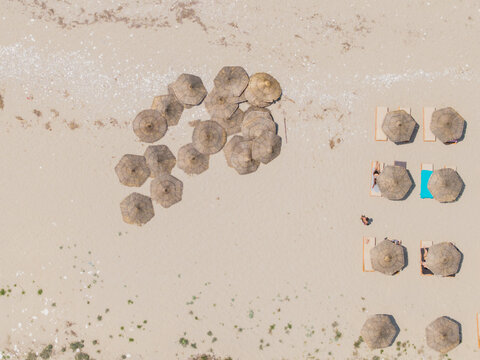 Aerial view of Kroreza Beach featuring rows of straw umbrellas and sun loungers on the sandy shore, Sarande, Vlore County, Albania.