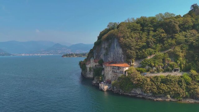 Aerial 4K drone video footage of Santa Caterina del Sasso monastery on the shores of Lake Maggiore, Italy, showcasing its dramatic lakeside setting. Hermitage Eremo di Santa Caterina del Sasso