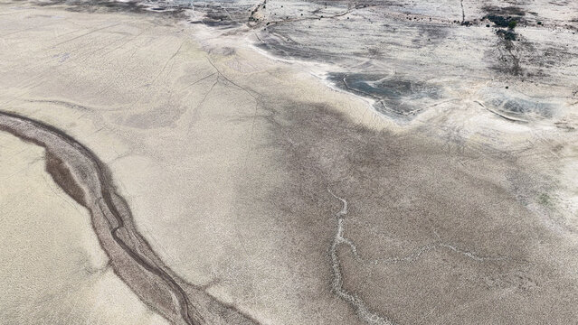 Aerial view of the arid Karoo landscape featuring a dry riverbed and cracked earth patterns in Beaufort West, Western Cape, South Africa.