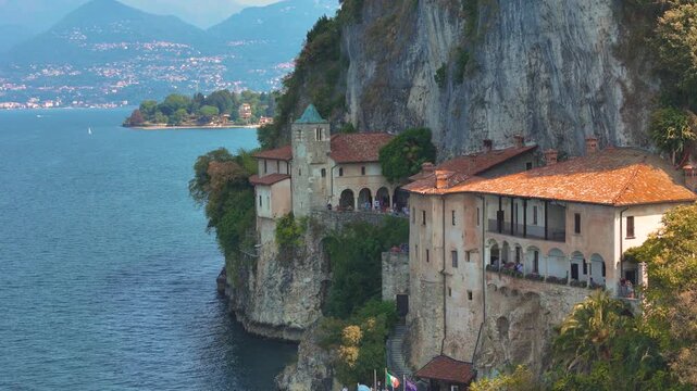 Santa Caterina del Sasso monastery on the shores of Lake Maggiore, Italy, showcasing its dramatic lakeside setting. Aerial 4K drone video footage of hermitage Eremo di Santa Caterina del Sasso