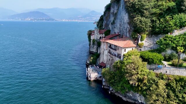 Santa Caterina del Sasso monastery on the shores of Lake Maggiore, Italy, showcasing its dramatic lakeside setting. Aerial 4K drone video footage of hermitage Eremo di Santa Caterina del Sasso