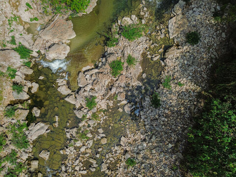 Aerial view of Sri Gethuk Waterfall featuring clear river water flowing over rocky terrain, lush green vegetation, and natural stone formations, Yogyakarta, Special Region of Yogyakarta, Indonesia.