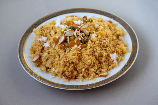 Fried crispy laccha semai dessert garnished with nuts raisins and grated coconut on ceramic plate. Traditional South Asian sweet dish prepared for Eid festival.