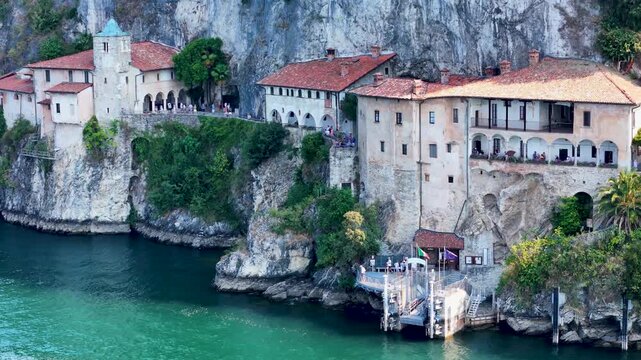 Aerial 4K drone video footage of Santa Caterina del Sasso monastery on the shores of Lake Maggiore, Italy, showcasing its dramatic lakeside setting. Hermitage Eremo di Santa Caterina del Sasso