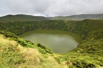 Volcanic crater, Lake Negra surrounded by green vegetation on Flores Island, rain clouds, Azores © Klara Bakalarova