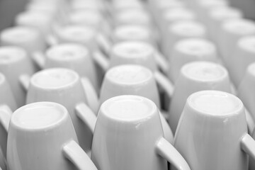 Fototapeta premium Clean row of empty white ceramic coffee mugs standing on table in minimalist cafe and restaurant kitchen, conceptual modern dishware texture pattern background for catering and office breakfast concep