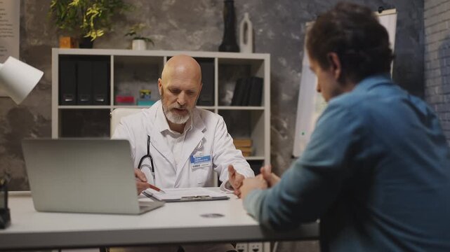 Doctor informs male patient of serious diagnosis during medical clinic check-up