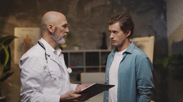 Doctor informs upset male patient of serious diagnosis and offers support
