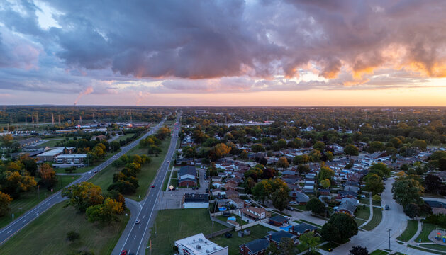 Aerial view of the suburban landscape at sunset, featuring a highway stretching into the distance, residential neighborhoods with houses and trees, Trenton, Michigan, United States.