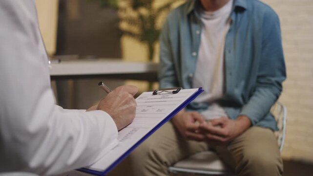 Doctor listens to male patient and takes notes during men's health consultation