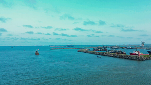 Aerial view of Tema Harbour with fishing boats docked along the stone breakwater in the calm blue waters of the Atlantic Ocean in Tema, Ghana.
