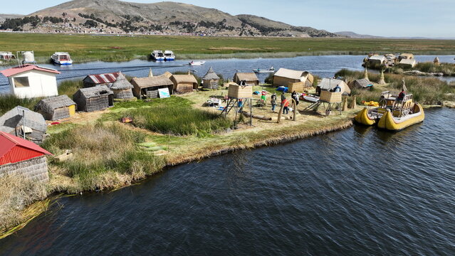 Aerial view of the Uros floating islands on Lake Titicaca with traditional reed houses and boats surrounded by water in Urus, Peru.