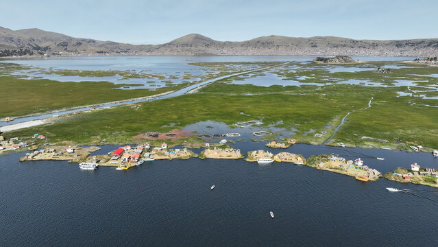 Aerial view of Lake Titicaca with its famous floating Uros islands, traditional reed houses, and boats on the water in Urus, Peru.