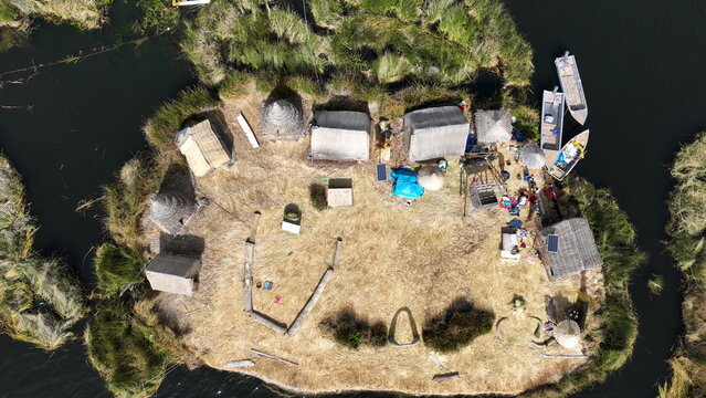 Aerial view of the Uros floating islands made of totora reeds on Lake Titicaca with traditional houses, small boats, and solar panels in Urus, Peru.