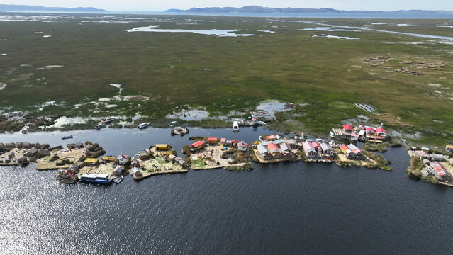 Aerial view of Lake Titicaca featuring the traditional floating islands of the Uros people with reed structures and boats on the water in Urus, Peru.