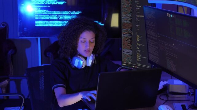 Female software developer working with multiple monitors display programming code in a modern technology workspace. coding, cybersecurity, digital technology, data processing, programming, innovation.
