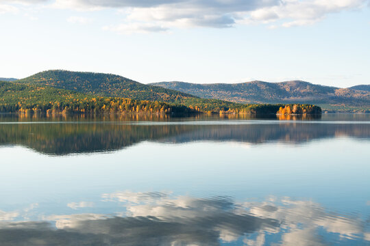 Turgoyak lake in Southern Urals, Russia.. Autumn mountains and sky with clouds are reflected in the water.
