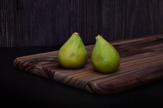 Two green figs on a wooden board
