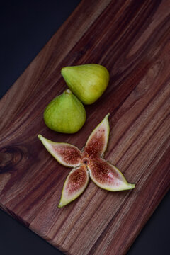 Fresh green figs and a sliced fig served on a wooden charcuterie board