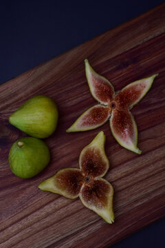 Decorative fresh green figs whole and sliced on a wooden board