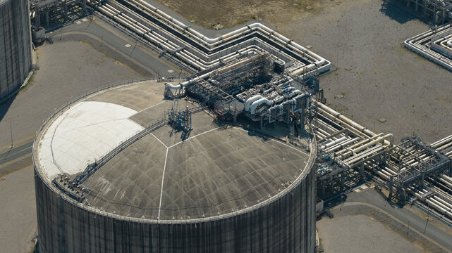 Aerial view of Dunkirk LNG Terminal showing large storage tank with complex piping infrastructure and industrial equipment in Loon-Plage, Hauts-de-France, France.