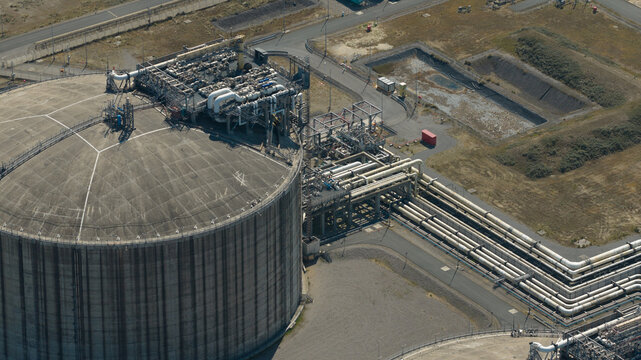Aerial view of Dunkirk LNG Terminal featuring a large storage tank and complex industrial piping infrastructure in Loon-Plage, Hauts-de-France, France.