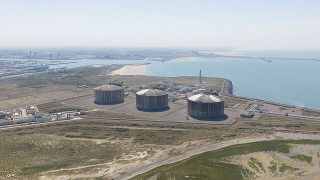 Aerial view of Dunkirk LNG Terminal featuring large storage tanks situated on the coast with industrial infrastructure and the sea in Loon-Plage, Hauts-de-France, France.