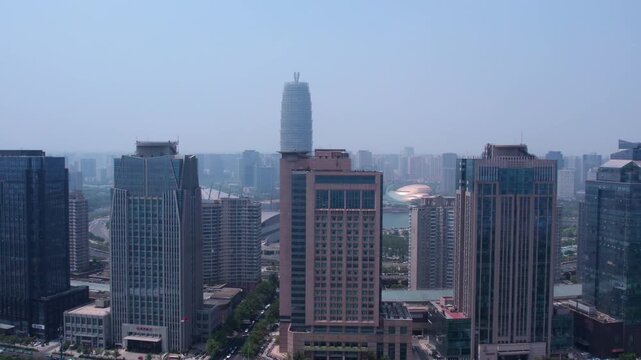 A daytime urban cityscape featuring multiple modern high-rise buildings forming a dense city skyline under a clear sky.