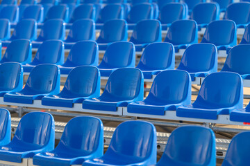 Fototapeta premium Vibrant rows of empty blue seats await eager spectators at a lively sports event during a sunny day