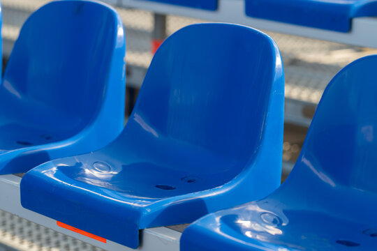 Bright blue plastic seats await eager spectators at an outdoor event under the sun inviting moments of excitement and joy
