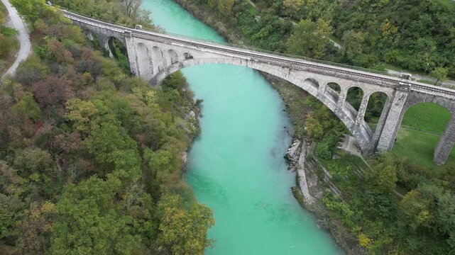 Majestic Solkan Bridge with its impressive stone arch spanning the turquoise Soca River. Scenic aerial view of the railway viaduct