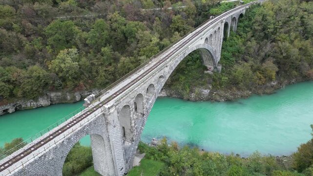 Stunning aerial footage showing the historic Solkan Bridge, the world's largest stone arch railway bridge, spanning the vibrant emerald Soca River