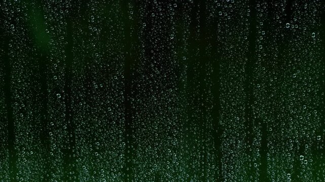 Melancholic view of water droplets on window glass during a dark rainstorm with light hail outside