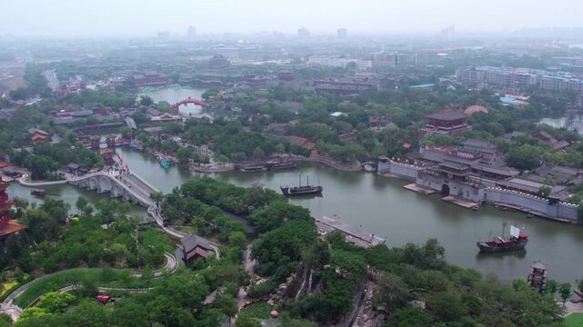 A high-angle aerial panorama of a historic scenic zone with traditional Chinese architecture, waterways and green vegetation.