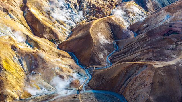 Aerial view of Kerlingarfjoll with colorful geothermal mountains, steam vents, and a winding river in Hrunamannahreppur, Iceland.