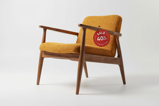 Mid-century modern armchair with yellow boucl&eacute; upholstery. Wooden lounge chair with red 40% sale tag. Retro furniture for interior design.