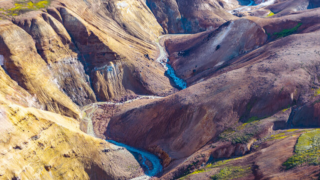 Aerial view of Kerlingarfjoll mountain range with winding river and geothermal volcanic landscape in Hrunamannahreppur, Iceland.