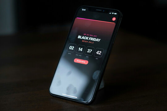 Black Friday mega sale app on smartphone screen, digital countdown timer for online shopping, mobile e-commerce promotion on dark background