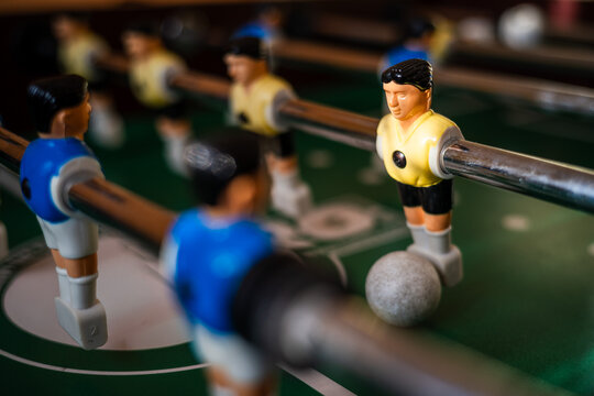 Foosball players competing around the ball on a table football game, representing teamwork, strategy, recreation and competitive indoor entertainment.