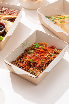 Healthy buckwheat porridge with vegetable tomato sauce and microgreens in takeaway craft paper box close up