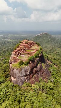 Aerial view of the historic Sigiriya Rock Fortress rising dramatically above the surrounding tropical landscape and dense jungle in Sri Lanka, 4k.