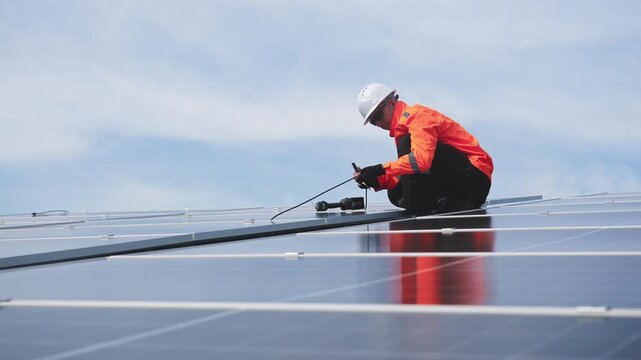 Technician installing solar panels on factory roof for green energy. A skilled technician in safety gear is working on a solar panel installation on rooftop. clean energy renewable power technology.