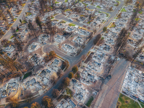 Aerial view of a residential neighborhood devastated by a wildfire, showing charred trees and the ruins of houses in Spokane, Washington, United States.