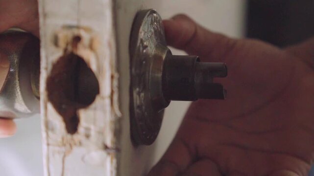 Handyman disassembling an old rusty doorknob for repair
