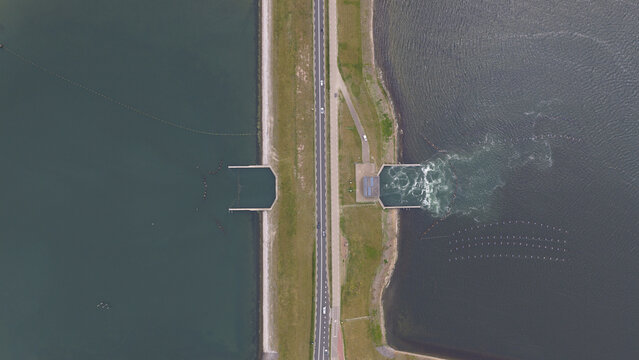 Aerial view of Zandkreekdam featuring a straight road running along the dam structure with water turbulence on one side and calm water on the other in Goes, Zeeland, Netherlands.