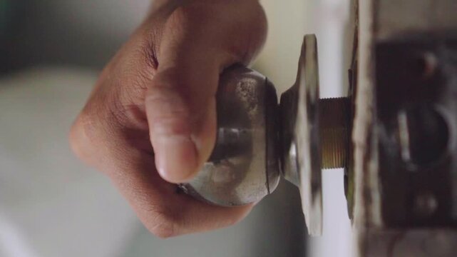 Hand turning old metal doorknob lock