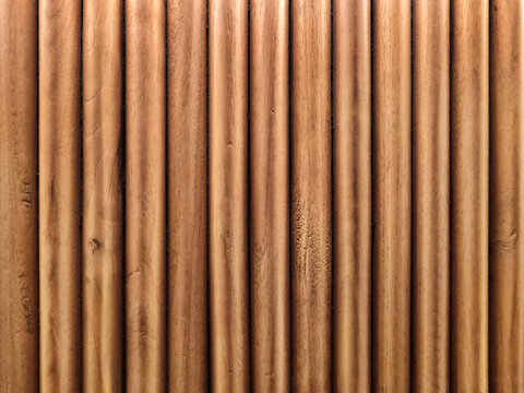 Background of texture and dark pattern of vertical wood plastic composite. Fluted wood panels with soft warm lighting from above have linear dark gradation shadow, dramatic and minimalist dimension.