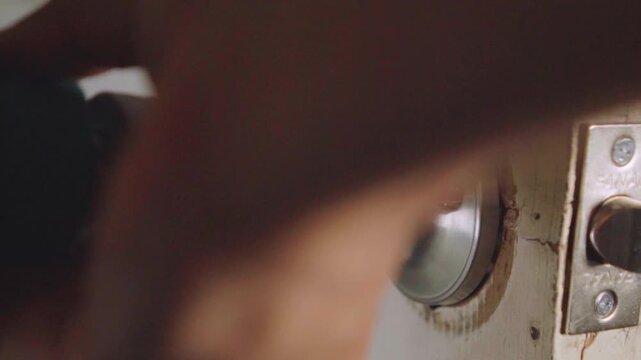 Worker using power drill to repair doorknob