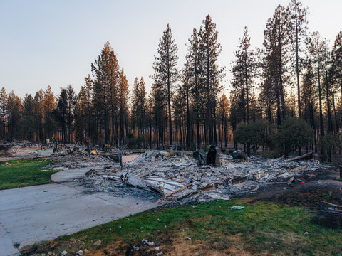 Aerial view of the aftermath of the Spokane wildfire, showing a destroyed home with charred debris, ash, and scorched pine trees in Spokane, Washington, United States.